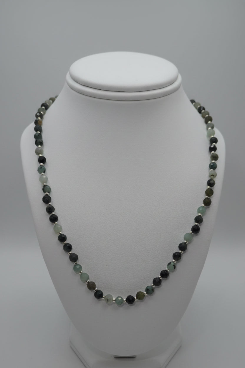 Necklace with green and black beads on a white mannequin bust.